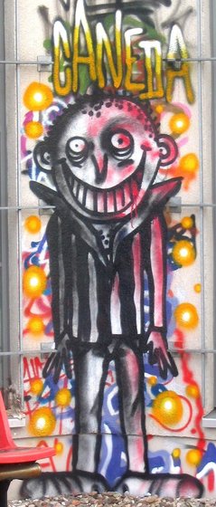 Wandmalerei eines breit grinsenden Mannes, überschrieben mit "Caneda"