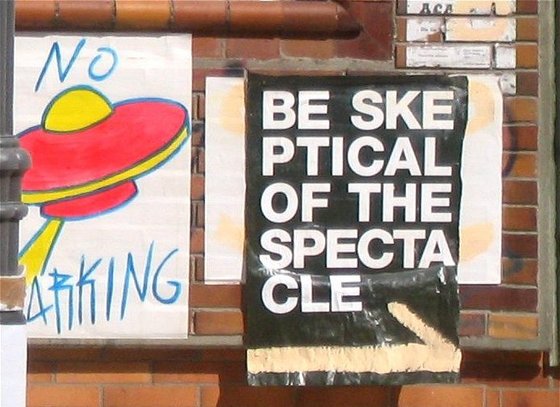 Ufo mit Schrift "No Parking", Schrift "Be skeptical of the spectacle"