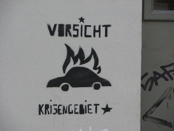 stilisiertes brennendes Auto mit dem Text "Vorsicht Kriesengebiet"