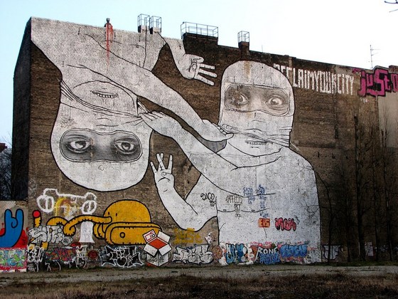 2 vermummte Gestalten, die an ihren Masken zerren