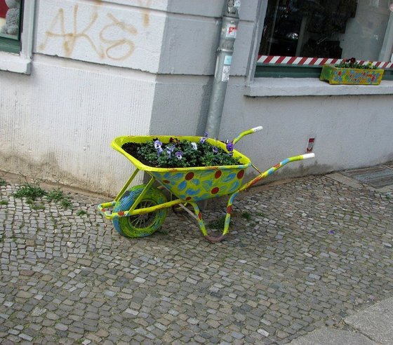 bunt angemalte Schubkarre, die als Blumenkasten dient