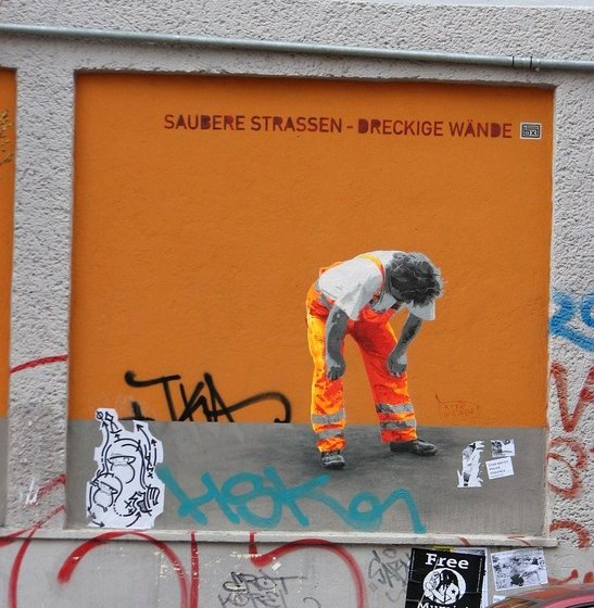 Wandmalerei eines erschöpft aussehenden Straßenreinigers, Schriftzug "Saubere Straßen - dreckige Wände"