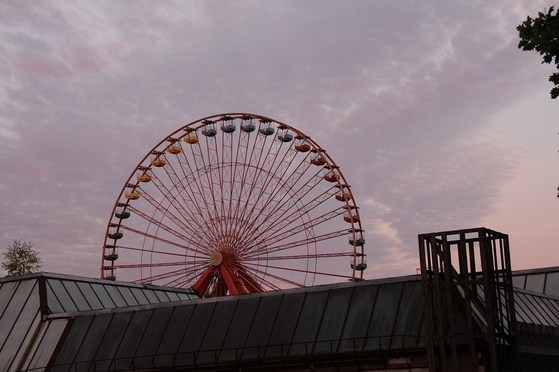 Riesenrad hinter einem Hausdach in der Dämmerung