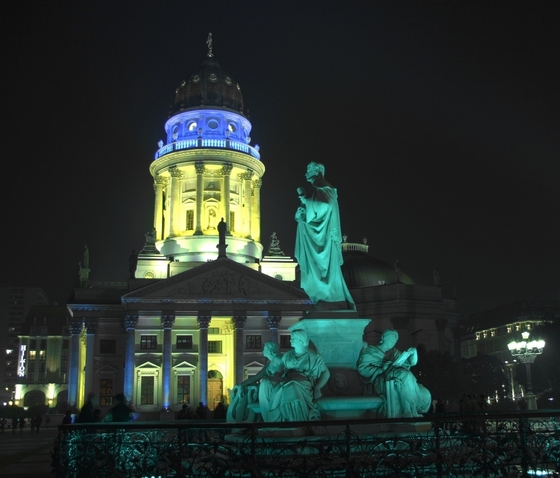 der Deutsche Dom blau und gelb angestrahlt, grün erleuchtete Schillerstatue im Vordergrund