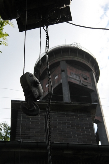 Flashenzug im Vordergrund, dahinter verschwommen ein Wasserturm