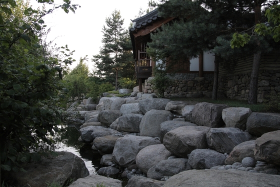 mit Bäumen bewachsenes, steiniges Ufer, koreanisches Haus