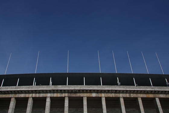 Frontalaufnahme des oberen Bereichs des Olympiastadions vor blauem Himmel