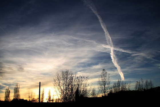 Wolkenformationen und Kondensstreifen im Sonnenuntergang