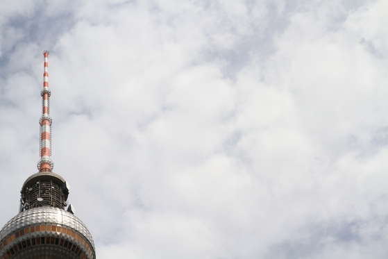 Spitze des Fernsehturms vor wolkigem Himmel