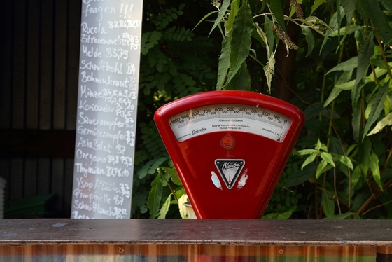 rote Waage an einem Tresen, Preistafel