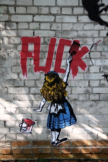 Wandmalerei: kleines Mädchen malt das Wort "FUCK" mit roter Farbe