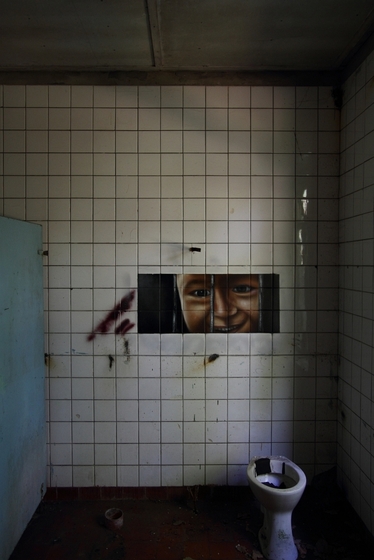 Malerei eines lächelnden Jungen hinter Gittern auf einer gefliesten Wand, Toilette