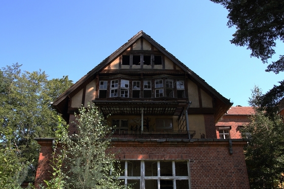 Giebel eines verfallenden Backsteingebäudes vor strahlend blauem Himmel