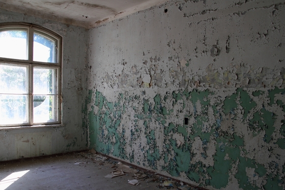 durch ein Fenster beleuchteter Raum, Farbe blättert von der Wand