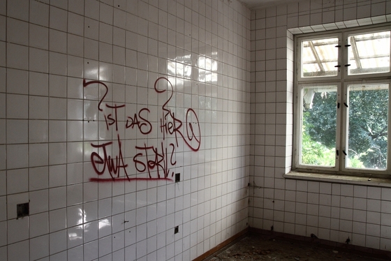 gefliester Raum, Graffito "ist das hier etwa steril" an der Wand