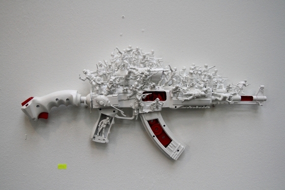 aus Plastikgeräten zusammengesetztes und mit Soldatenfiguren verziertes Gewehr