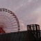 Riesenrad hinter einem Hausdach in der Dämmerung